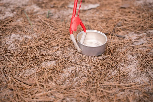 Recoger herramienta cerca de contenedor de aluminio en el suelo en los bosques - foto de stock