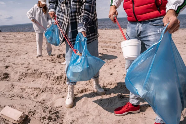 Voluntarios recogiendo basura en bolsas de basura - foto de stock