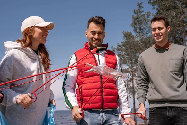 Happy volunteers collecting garbage with pick up tools — Stock Photo