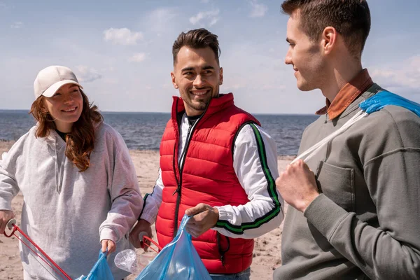 Happy men and woman picking up garbage in trash bags — Stock Photo