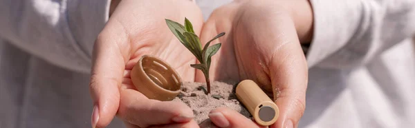 Vue recadrée de la femme tenant la batterie, capuchon en plastique et plante verte dans les mains, bannière — Photo de stock