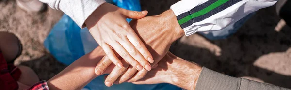 Top view of volunteers holding hand together above trash bag, banner — Stock Photo