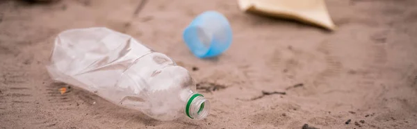 Пластикова пляшка біля сміття на розмитому піску, банер — стокове фото