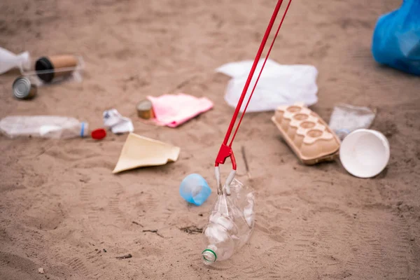 Захоплювач з пластиковою пляшкою біля штапика на піску — стокове фото