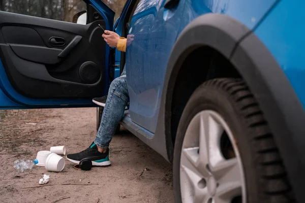 Vista recortada del hombre de pie en el suelo cerca de coche y basura, concepto de ecología - foto de stock