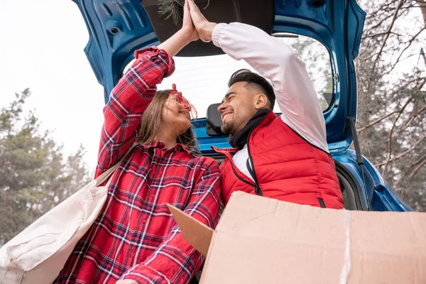 Niedrigwinkel-Ansicht der glücklichen Frau lächelt, während sie High Five mit Mann in der Nähe Auto — Stockfoto