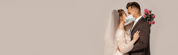Side view of young newlyweds in safety masks standing face to face isolated on grey, banner — Fotografia de Stock