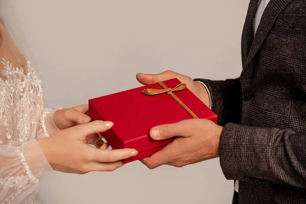 Cropped view of groom presenting gift to bride isolated on grey — Fotografia de Stock