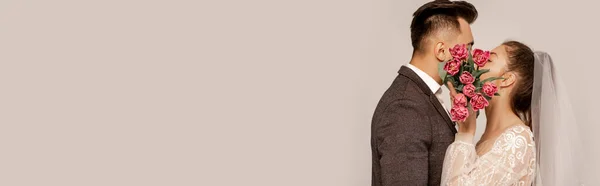 Молоді молодята цілуються під час затемнення облич з тюльпанами ізольовані на сірому, банер — Stock Photo