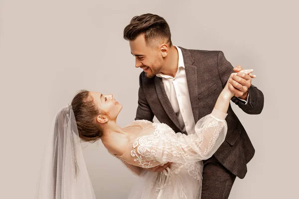 Elegant couple of newlyweds dancing isolated on grey with lilac shade — Stock Photo