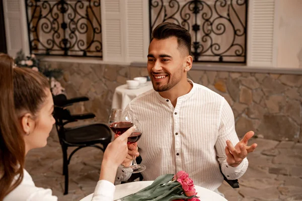 Happy man clinking wine glasses with blurred woman while dating in cafe — Stock Photo