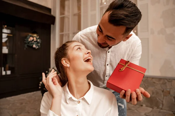 Erstaunte Frau schaut Freund mit Geschenkbox im Café an — Stockfoto