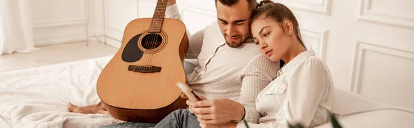 Man with acoustic guitar looking at mbira in hands of girlfriend, banner — Stock Photo