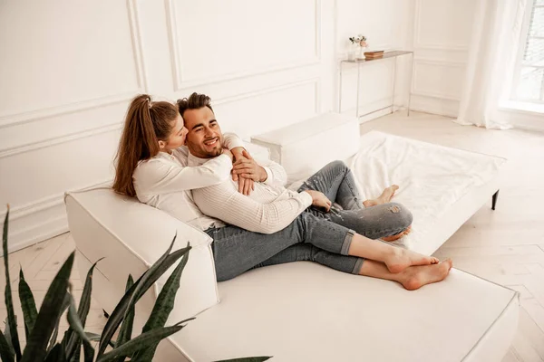 Young barefoot couple in jeans resting on couch in living room — Foto stock