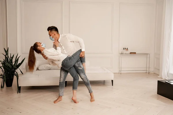 Young couple in safety masks and jeans dancing in living room — Photo de stock