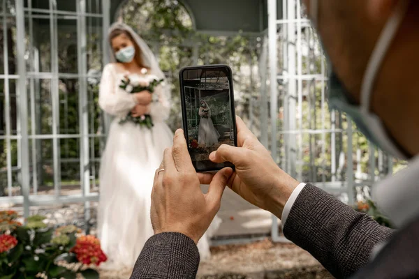 Selective focus of smartphone in hands of groom taking photo of bride — Stock Photo