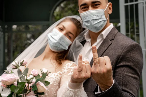 Couple of newlyweds in safety masks showing wedding rings at camera — Fotografia de Stock