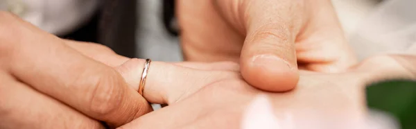 Partial view of man putting wedding ring on finger of bride, banner — Stock Photo