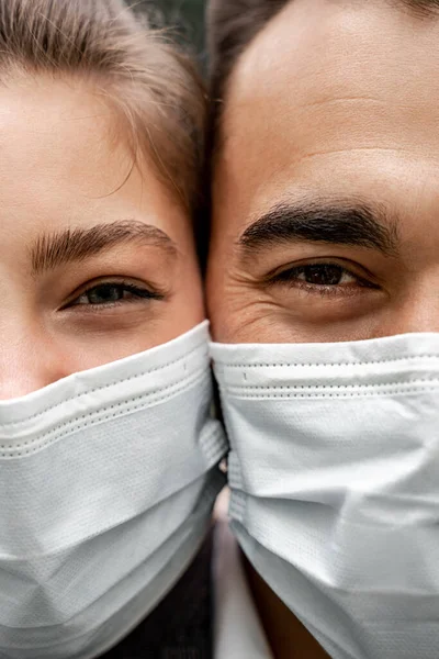 Обрезанный вид молодых мужчин и женщин в медицинских масках, смотрящих в камеру — стоковое фото