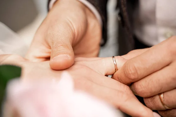 Cropped view of man putting wedding ring on finger of bride, blurred foreground — Stock Photo