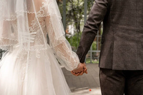 Partial view of newlyweds holding hands outdoors — Fotografia de Stock