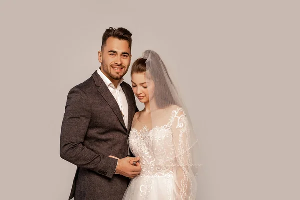 Happy man smiling at camera near charming bride isolated on grey — Stock Photo