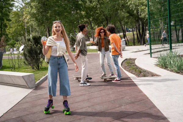 Patineur heureux debout avec cocktail près d'amis multiethniques — Photo de stock