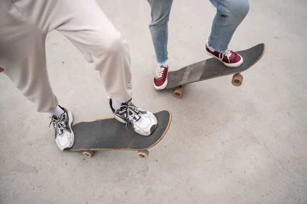Vista cortada de amigos em tênis andar de skate ao ar livre — Fotografia de Stock