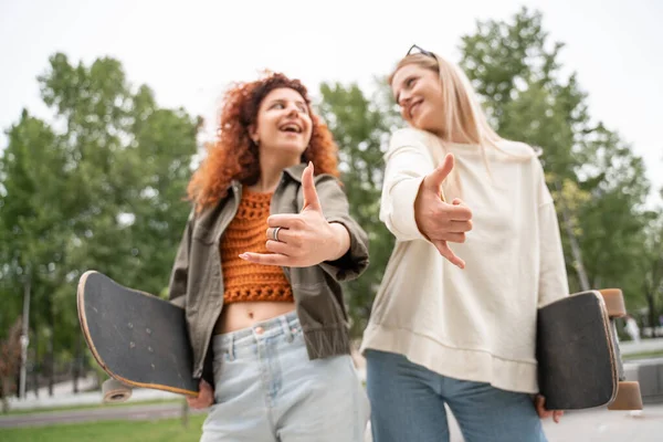 Blick auf verschwommene Skater, die Shaka-Geste zeigen, während sie einander anlächeln — Stockfoto