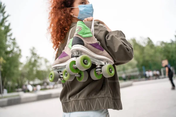 Mulher desfocada em máscara médica segurando patins no parque de skate — Fotografia de Stock