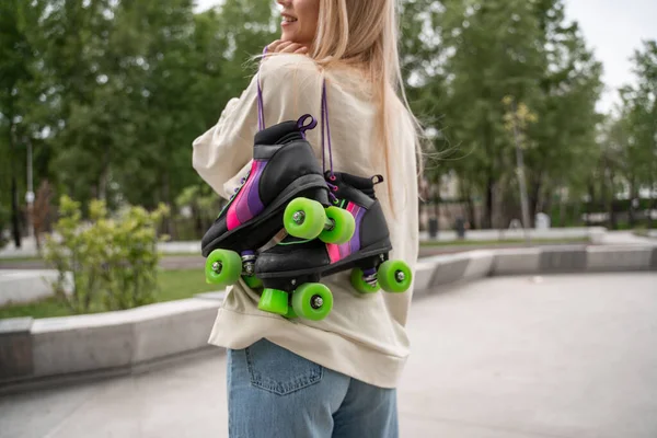Cropped view of smiling woman holding roller skates in skate park — Stock Photo