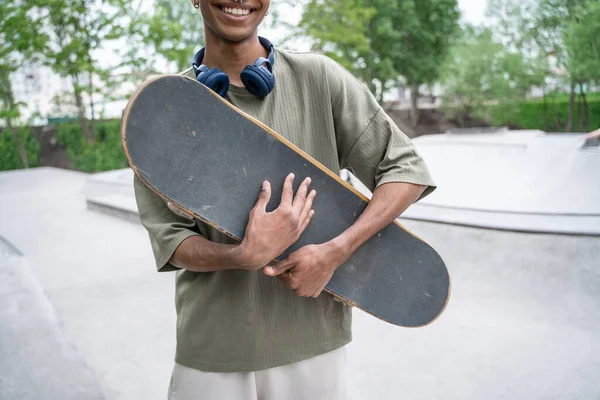 Partial view of african american man smiling while holding skateboard — Stock Photo
