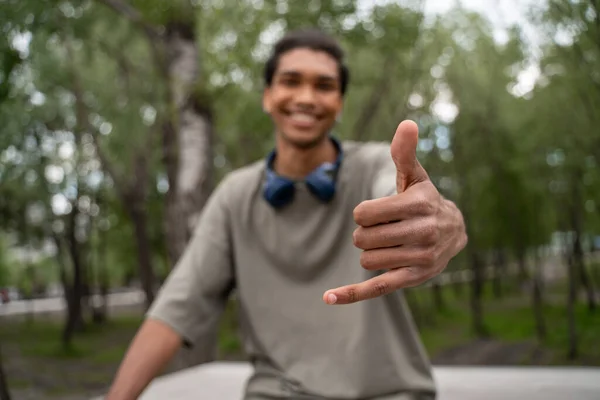 Blurred african american man smiling and showing hang loose gesture outdoors — Stock Photo