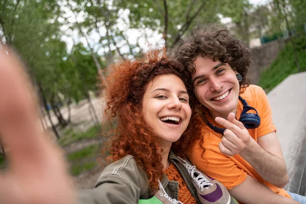 Rizado, feliz hombre y mujer tomando selfie en parque - foto de stock