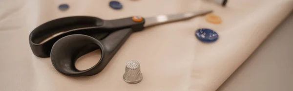 Close up view of sewing scissors and thimble on cloth, banner — Stock Photo