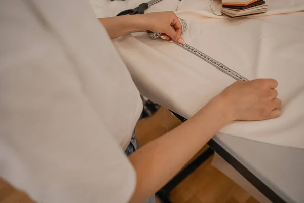 Cropped view of designer measuring cloth in studio — Stock Photo