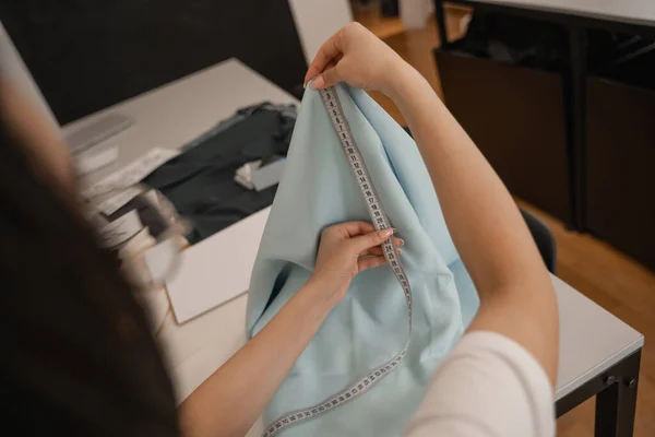 Cropped view of blurred designer holding fabric and tape measure — Stock Photo