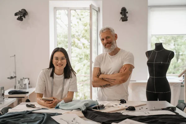 Lächelnde multiethnische Designer blicken in Werkstatt in die Kamera — Stockfoto