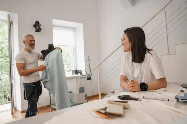 Asiático designer sorrindo para confuso colega em estúdio — Fotografia de Stock