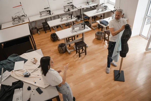 Overhead view of interracial designers talking near mannequin in studio — Stock Photo