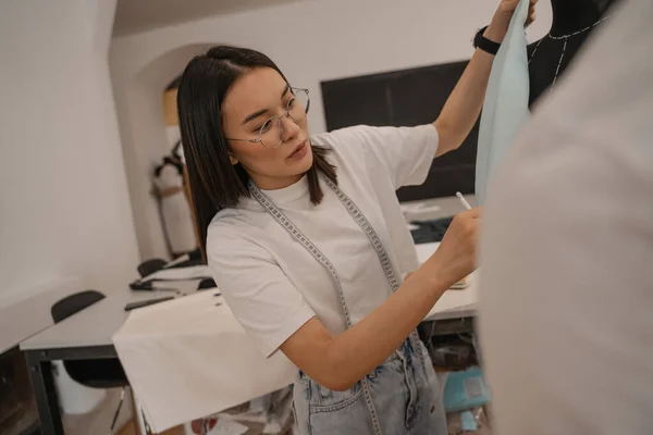 Diseñador asiático trabajando con tela y maniquí - foto de stock