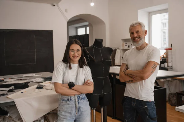 Multiethnic designers with crossed arms looking at camera near mannequin — Stock Photo