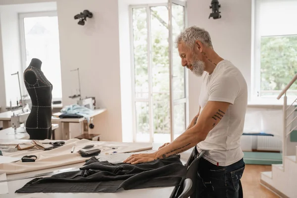 Side view of mature designer working with cloth in studio — Stock Photo