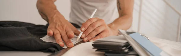 Cropped view of mature designer working with cloth and sewing pattern, banner — Stock Photo