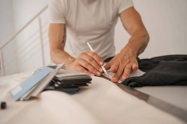 Cropped view of mature designer working with sewing pattern and cloth — Stock Photo