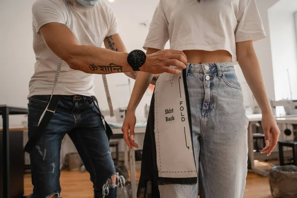 Cropped view of designer holding cloth and sewing pattern near customer in atelier — Stock Photo