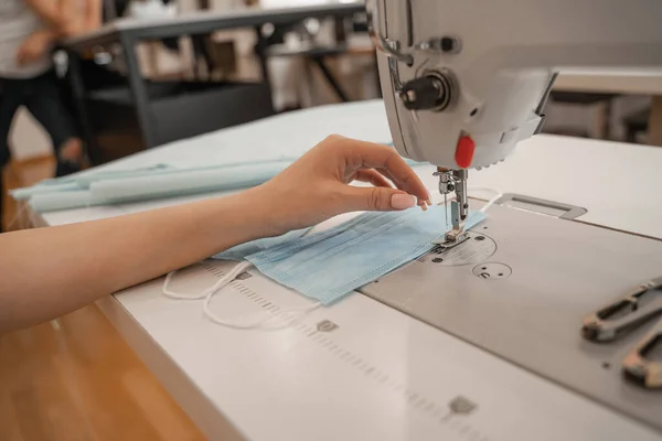 Ausgeschnittene Ansicht einer Näherin, die mit medizinischer Maske und Nähmaschine arbeitet — Stockfoto