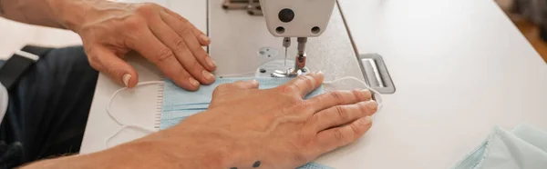 Cropped view of tailor sewing medical mask in atelier, banner — Stock Photo