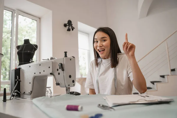 Designer asiático ter ideia perto de máquina de costura no atelier — Fotografia de Stock