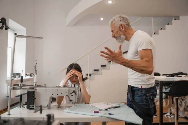 Designer arrabbiato in piedi vicino spaventato asiatico collega in atelier — Foto stock